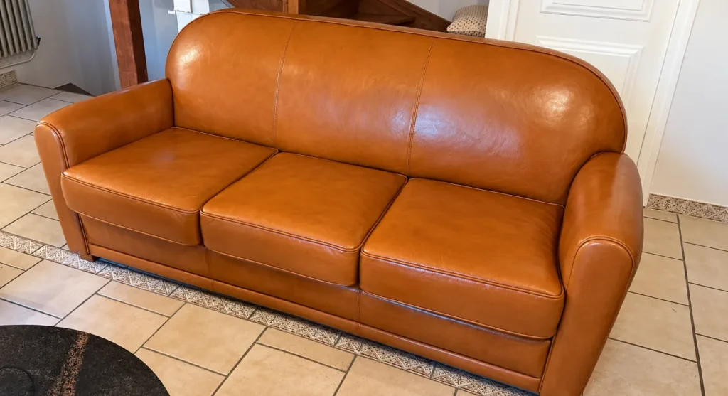 Canapé club en cuir cognac après rénovation, teinte uniforme et brillante