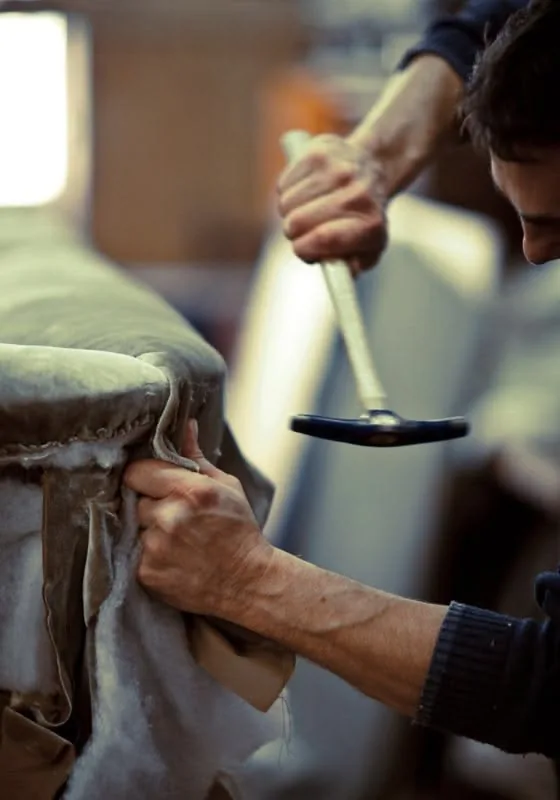 Tapissier fixant la garniture d'un siège au marteau de tapissier