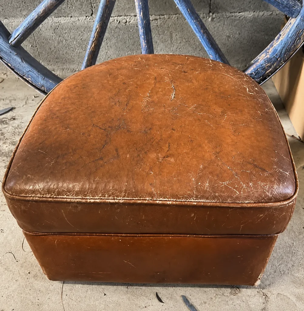 Pouf club au revêtement cognac griffé avant réfection